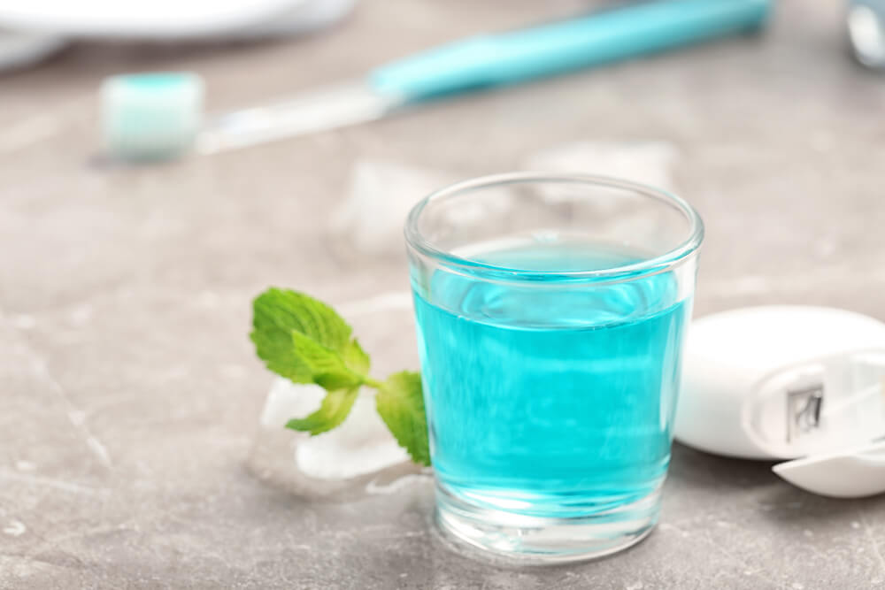 Glass with mouthwash on marble background